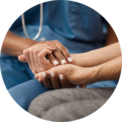 Partner_Photo1 A healthcare worker in blue scrubs gently holds a patients hand, offering comfort and support. The focus is on their hands, conveying care and compassion in a medical setting.